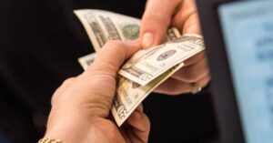 (person handing another person cash)