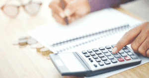 (Close-up of a person using a calculator and writing in a notebook, symbolizing personal budgeting and financial planning to reduce debt.)