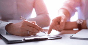 (Close-up of a person signing a legal document with guidance, representing professional help with debt settlement agreements.) 